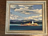 Full view of the framed painting showing the lighthouse on rocky shore with ocean and hills background.
