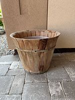 Large wooden planter pot shown from the side and angled view, displaying wood grain and metal band.