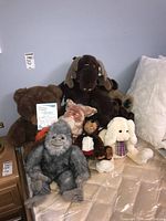 Photo showing the full grouping of plush animals including Furby manual visible, various animals such as moose, fox, teddy bear, gorilla and poodle visible, giving scale and variety of lot contents.