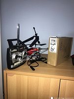 Gyro RC Helicopter, remote control, and box for TV mount on wooden furniture.