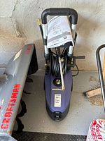 Top view of Simoniz electric pressure washer with hose and wand attached, showing handle with Simoniz logo and instruction manual.