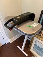 Left side angled view of the SteamFast SF-680 steam press showing handle, pressing surface, and portion of stand.