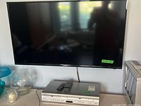 Wall-mounted Sharp flat-screen TV with Samsung DVD/VHS combo player on counter below.