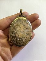 Front view of engraved sterling silver locket held in hand