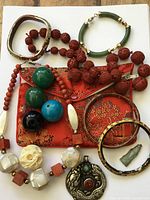 Overall lot view showing necklaces, bangles, pendants, beads, and pouch