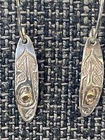 Front view of both earrings showing engraved hummingbird motif and gold eyes