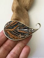 Front view of brooch on fingers showing inlay detail