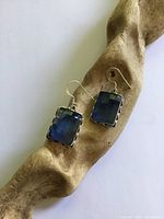 Pair of earrings on wood prop showing overall design