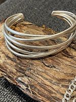 Close-up of multi-wire cuff bracelet resting on wood prop