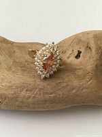 front view of ring showing marquise peach crystal and halo