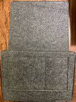 Full view of grey felt bedside caddy unfolded showing external pockets and insert flap