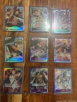 Nine sleeved holographic One Piece trading cards arranged in a 3×3 grid on a wood surface