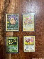 all four Pokémon cards in sleeves on wooden surface