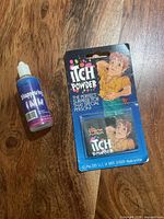 Bottle of disappearing ink and packaged itch powder on wood surface