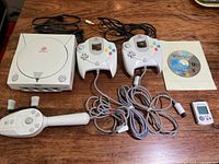 Lot overview showing Dreamcast console, two controllers, fishing rod controller, VMU, game disc, and cables