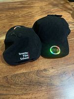 Two black corduroy hats showing embroidered logos and corduroy texture