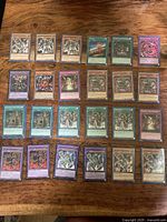 Twenty Yu-Gi-Oh! cards laid out in four rows on wood surface