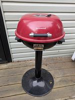 Closed red dome lid of the electric grill showing the black handle and Techwood branding