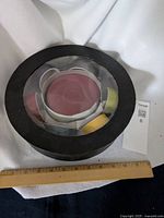 Top view of the sealed round box containing the colorful espresso cup set with black lid.