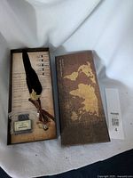 Feather quill pen set inside box with vintage map design lid.