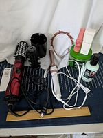 Full view of the hair care items arranged showing spin air brush, curling iron, hair products, hair band, and carry case.