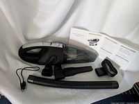 Main photo of handheld cordless vacuum with all attachments and instruction manuals laid out on white background.