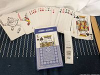 Full spread of jumbo playing cards including face cards and numbered cards with two jokers visible, blue card box shown