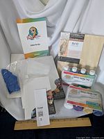 Paint pour kit components including acrylic pouring paint sets, gloves, canvases, birch wood panels, and pour cup
