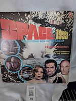 Front cover of the Space 1999 album showing the title, images of cast members, and a space explosion.