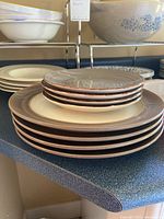 Stacked assorted plates and bowls on kitchen counter, showing variety of sizes and colors