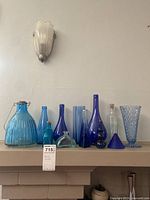 Various blue glassware including bottles, vases, and decorative pieces arranged on a mantle.