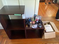 Photo of dark brown cubed cabinet with four compartments displaying various home and office supplies on and around it.