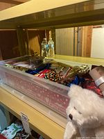 Box with assorted Christmas wrapping paper, ribbons, bows, and a white plush teddy bear nearby.