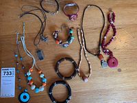 Photo of assortment of costume jewelry on wooden table, including necklaces and bracelets with beads in various colors and materials.