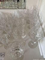 Wide view showing multiple crystal glasses arranged on a white surface reflecting light.