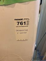 Label on the side of a white appliance with maxsold sticker 761 stating 'Dehumidifier & Heater'