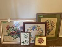 Set of five framed needlepoint artworks including large floral bouquets and smaller pieces.
