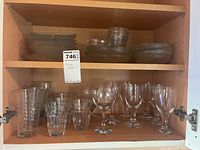 Shelved glassware including large and small drinking glasses, and stemmed wine glasses