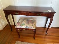 Full view of the hall table and floral upholstered bench on wooden floor.
