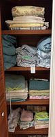 Overall view of shelves with assorted folded linens including sheets, towels, and covers in various colors and patterns.