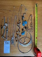 Full lot overview showing four ladies watches and nine different costume jewelry necklaces including silver-tone chains and turquoise stone pendants, with tape measure for scale.