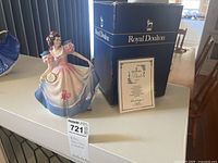 Photo displaying the Royal Doulton Angela figurine, the original blue and white Royal Doulton box and the certificate of authenticity in front.