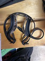 Protective goggles with black adjustable strap and clear lenses on wooden surface