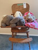 Vintage wooden highchair with three stuffed animals placed on the seat and tray.