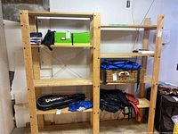Side view of the assembled wooden shelving unit in a basement setting containing various items on some shelves.