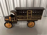 Front and side view of cast iron truck with yellow-orange wheels and 'Junior Supply Co.', 'New York', and 'Philadelphia' markings on cage sides.
