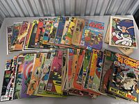 Photo showing a large selection of various comic books with colorful covers from different series stacked on a surface.