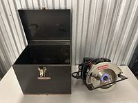 Open black metal box showing inside storage space and hinged lid with Craftsman logo on front.