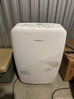 Front view of Garrison portable air conditioner showing white body with some dirt and scuff marks. Control panel on top of the unit is visible but mostly not readable in this photo.