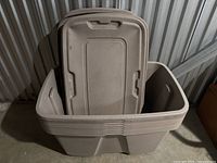 Set of six large beige plastic storage totes stacked with their lids leaning inside them.